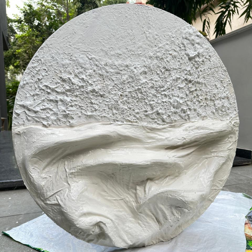 Round stone slab with a textured surface on a white cloth outdoors.
