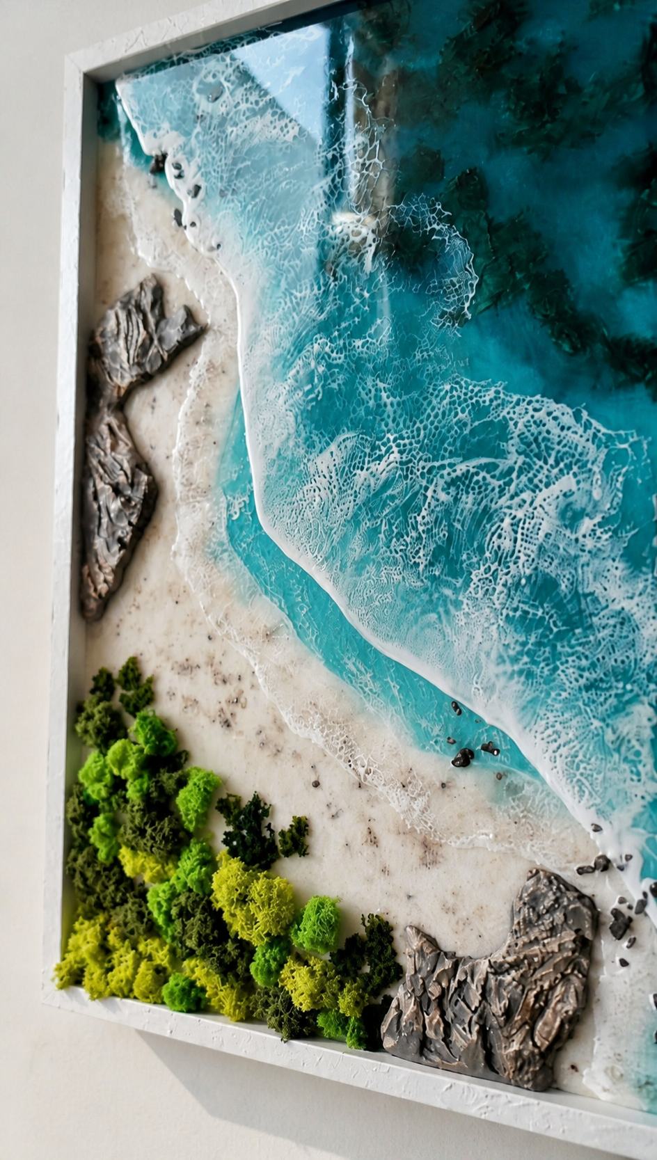 Close up of handcrafted turquoise ocean resin art with textured beach and rocks